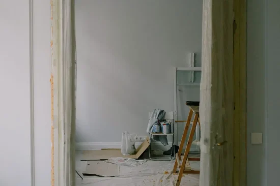 Open door in cellophane with construction materials on floor in room of new flat